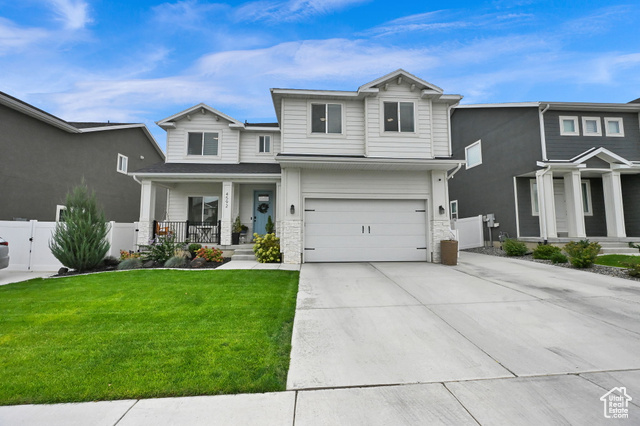 View of front of property featuring a front lawn, covered porch, and a garage