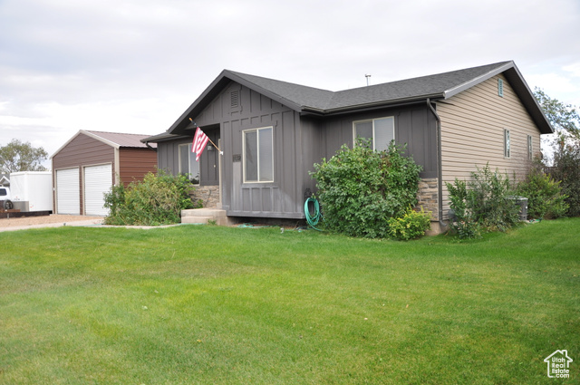 View of front of home featuring a front lawn, an outdoor structure, and a garage