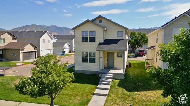 View of front of property featuring a mountain view, a garage, and a front lawn