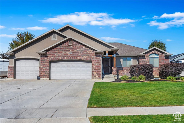 View of front facade featuring a garage and a front lawn