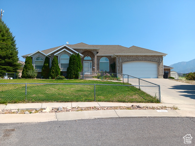 Ranch-style house featuring a mountain view, a front lawn, and a garage