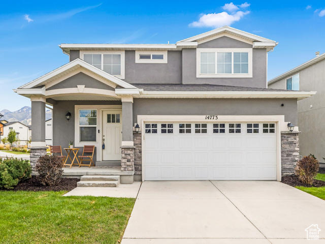 View of front of home featuring a porch, a garage, and a front yard