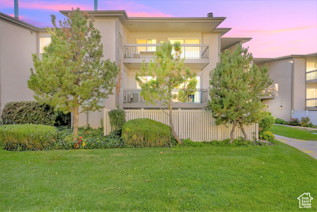 Property exterior at dusk with a lawn and a balcony