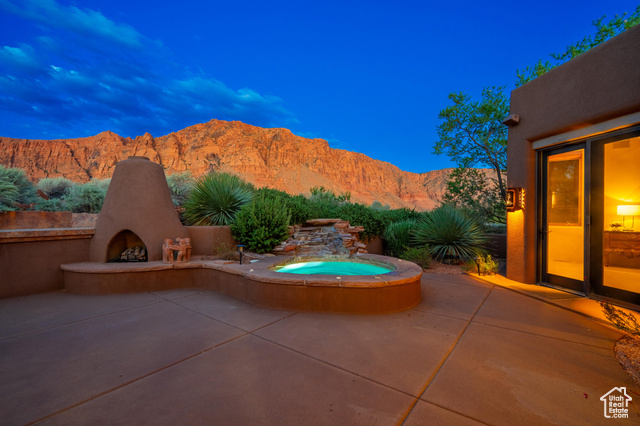 View of patio / terrace with an outdoor fireplace, a mountain view, and an in ground hot tub