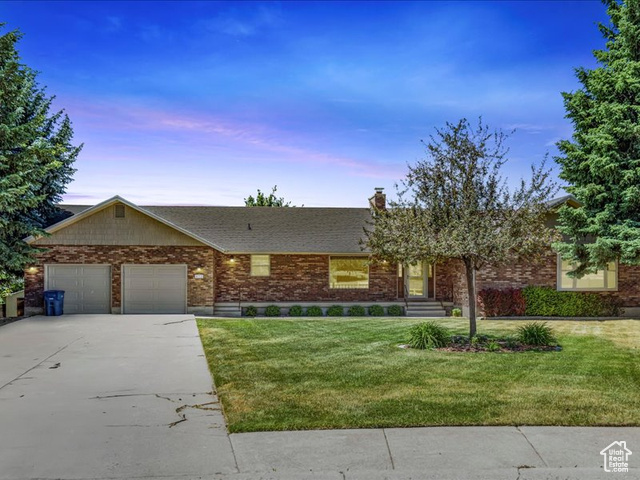 Single story home with a garage and a lawn