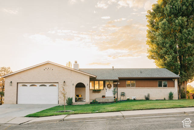 Ranch-style home featuring a garage and a yard