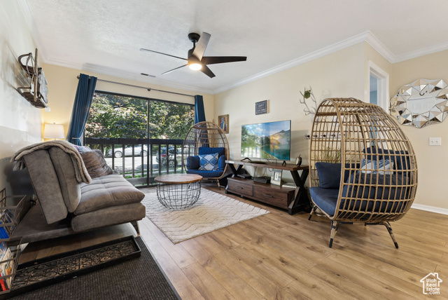 Living room with ceiling fan, ornamental molding, and hardwood / wood-style floors