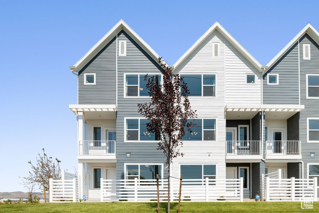 Townhome / multi-family property featuring a balcony and a front lawn