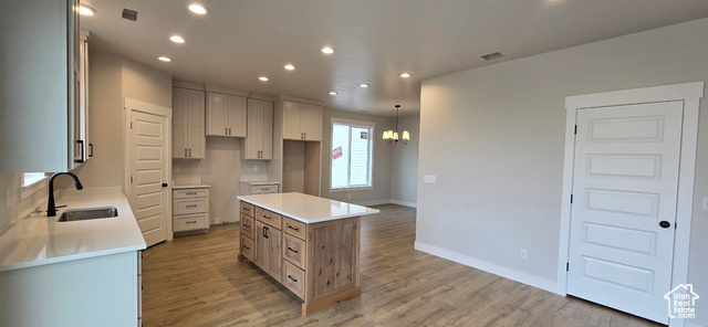 Kitchen with sink, a kitchen island, pendant lighting, and hardwood / wood-style flooring