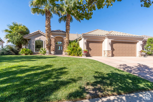 Mediterranean / spanish-style house with a garage and a front lawn