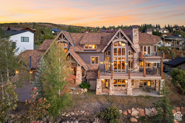 Back house at dusk featuring a patio and a balcony