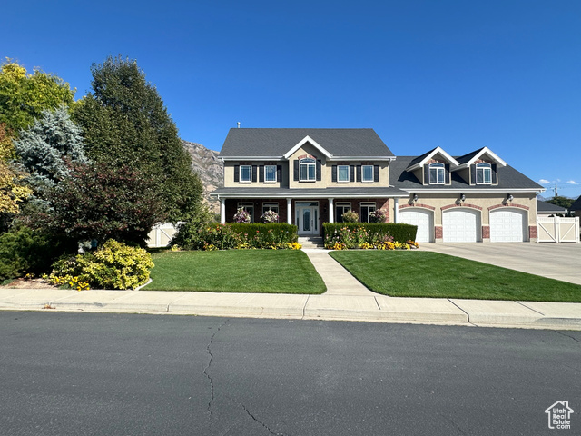 View of front of home with a garage, a front lawn, and covered porch