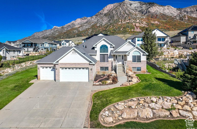 View of front of home with a front yard, a mountain view, and a garage