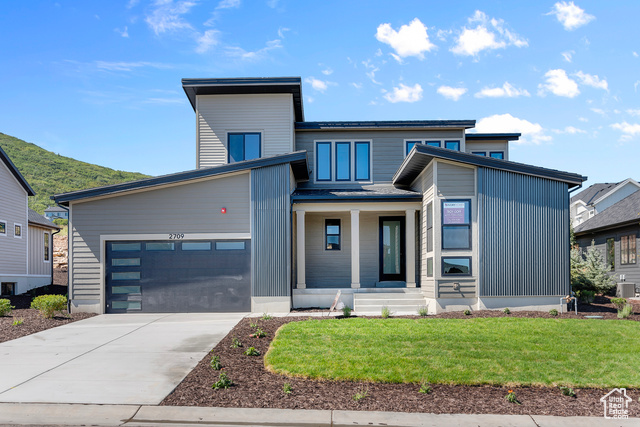 Modern home featuring a mountain view, a garage, and a front lawn