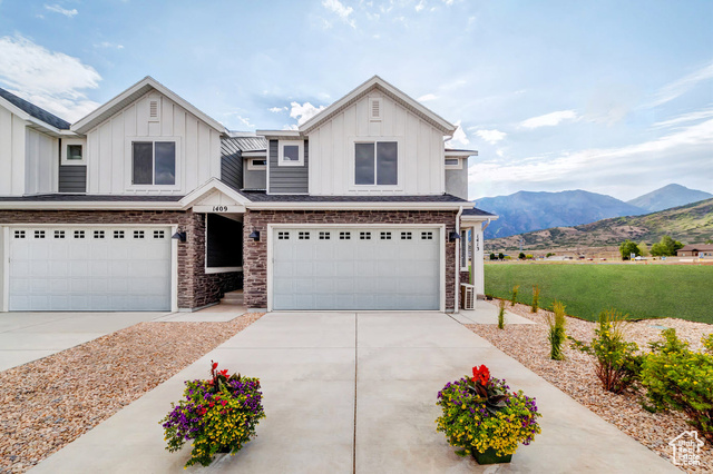 View of front of house with a mountain view, a front yard, and a garage