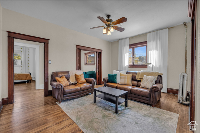 Living room with ceiling fan, cooling unit, and dark wood-type flooring