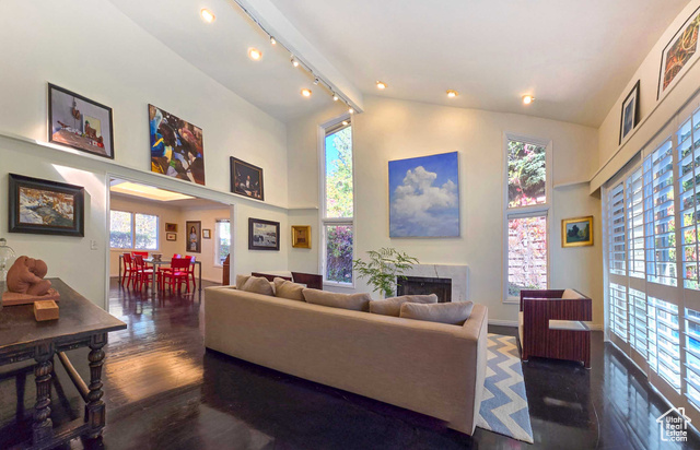 Living room with a towering ceiling and dark wood flooring, featuring a fire place and track lighting