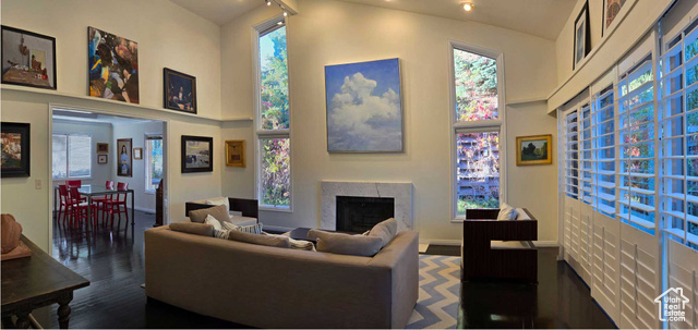 Living room with a towering ceiling and dark wood-type flooring, featuring a fire place