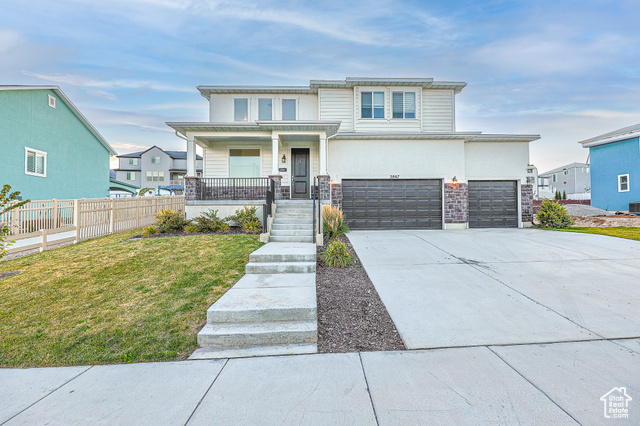 View of front of home featuring a front lawn, covered porch, and a garage