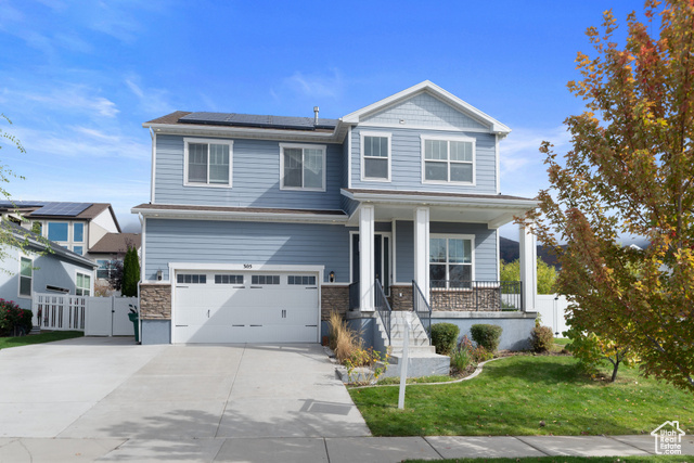 Craftsman inspired home with a garage, a front lawn, solar panels, and a porch