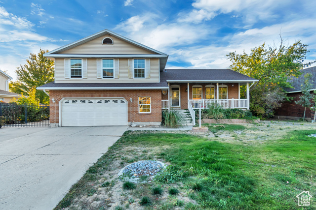 Split level home featuring a front yard, a porch, and a garage