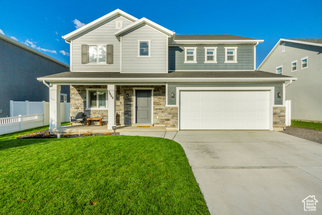 View of front facade featuring a garage, a front lawn, and covered porch