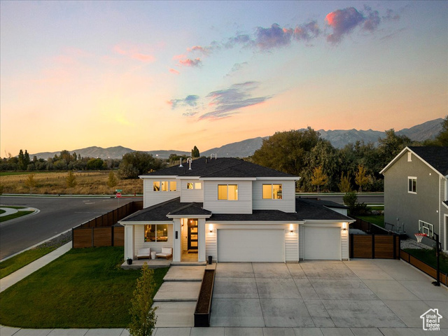 View of front of home with a yard, a mountain view, and a garage