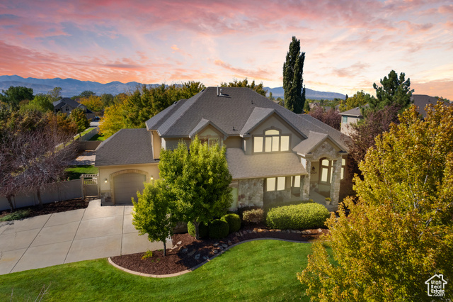 View of front of property with a mountain view, a garage, and a lawn