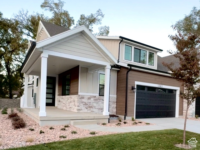 View of front facade with a garage, a porch, and a front lawn