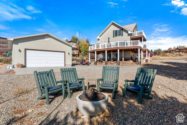 Back of property featuring a deck, a fire pit, and a garage