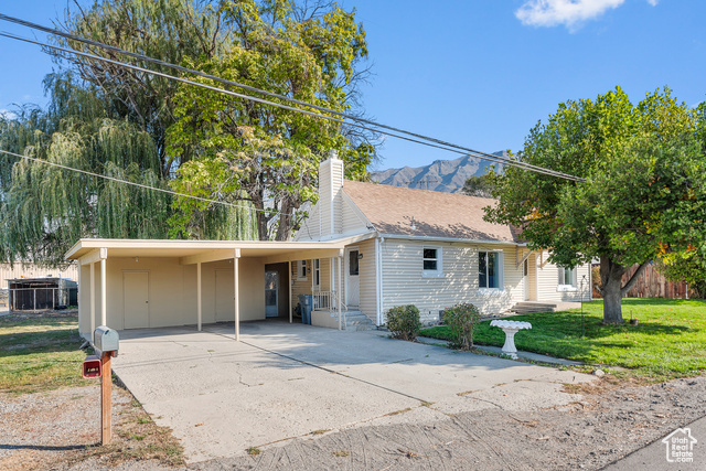 View of front facade with a mountain view, a front lawn, and a carport