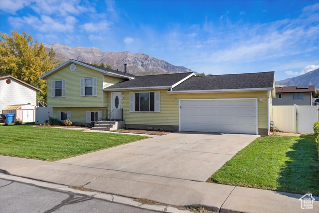 Tri-level home with a mountain view, a front yard, and a garage