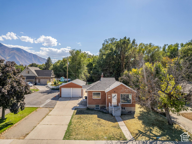 View of front of house with a garage, a front yard, and a mountain view