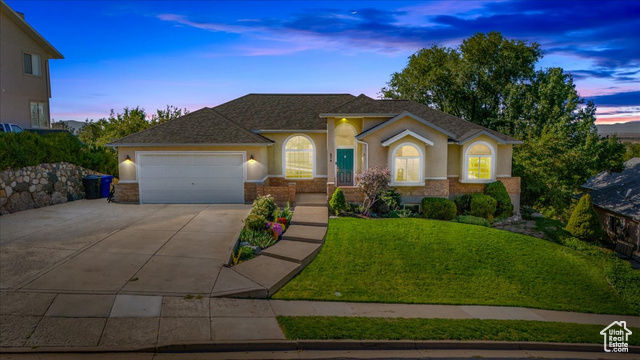 View of front of house with a garage and a yard