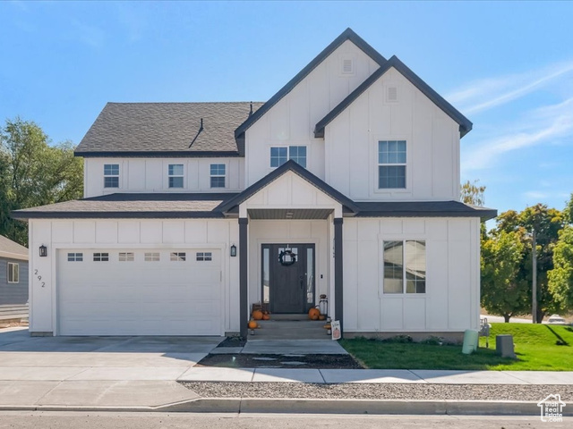 Modern farmhouse style home featuring a front lawn, central AC unit, and a garage