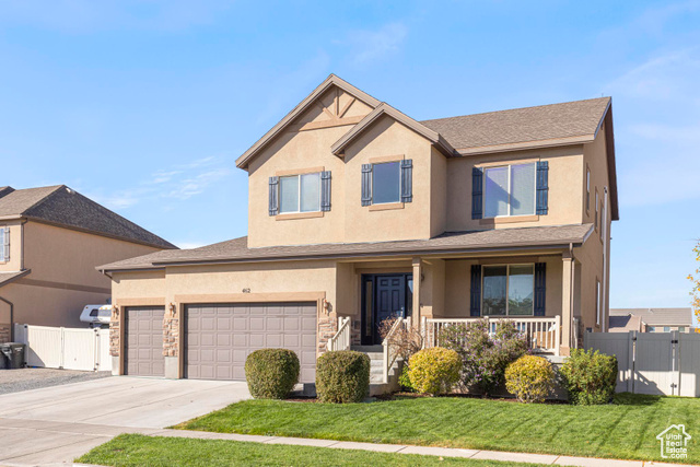 View of front of property with a porch, a front yard, and a garage