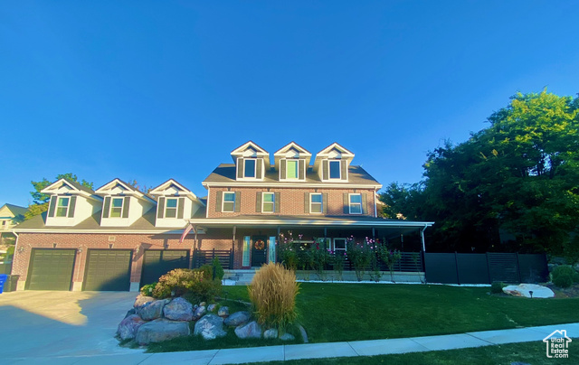 View of front facade featuring a garage, a front lawn, and covered porch