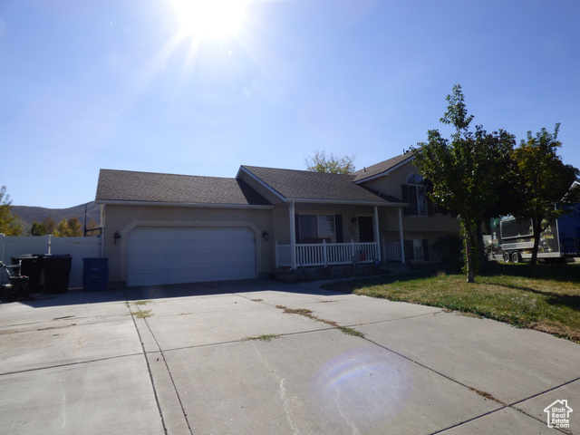 View of front of home featuring a mountain view, covered porch, a front yard, and a garage