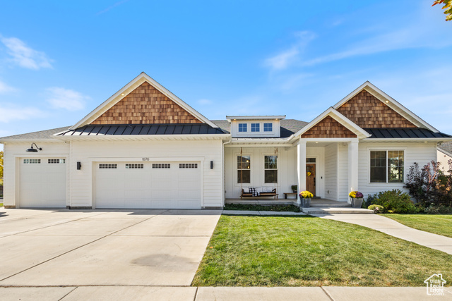 View of front facade with a front yard, a garage, and covered porch