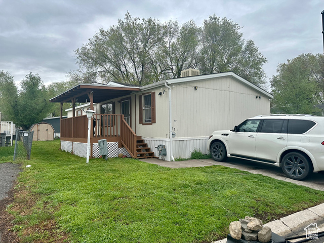 View of side of home featuring a storage shed and a yard