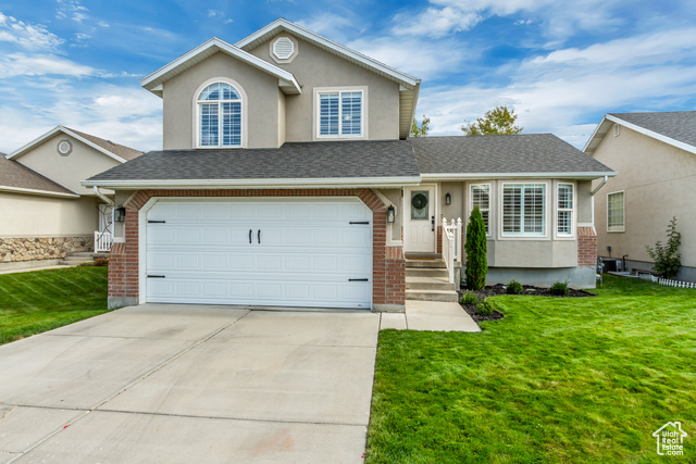 View of front of house featuring a front lawn and a garage