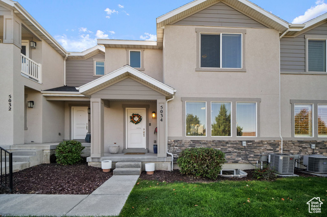 Townhome / multi-family property featuring central air condition unit and a front yard