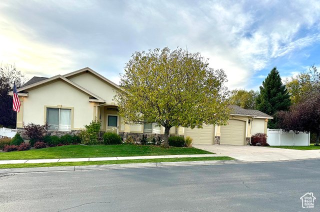 View of front facade featuring a front lawn, a two-car oversized garage and fenced yard with beautiful landscaping