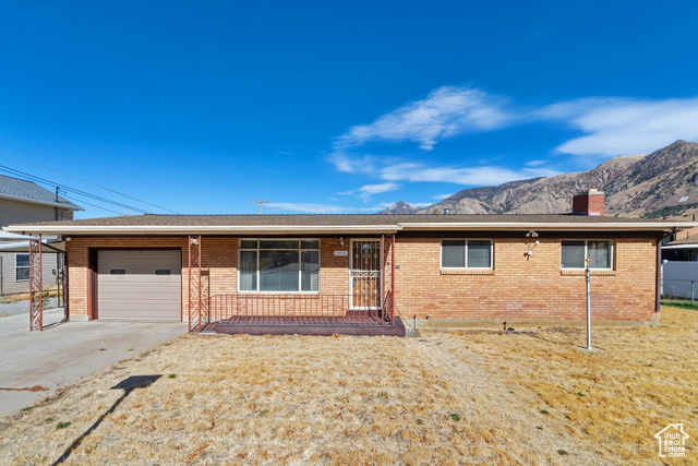 Ranch-style house featuring a mountain view, a front yard, and a garage