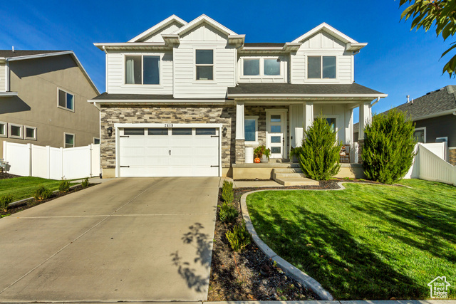 View of front of home with covered porch, a front lawn, and a garage