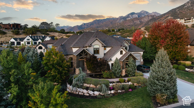 View of front facade with a garage, a mountain view, and a lawn