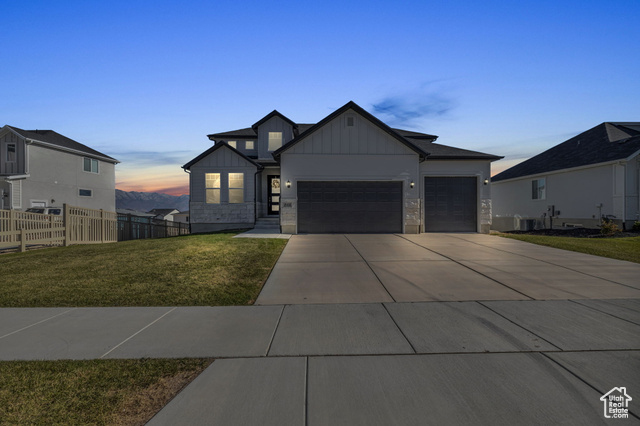 View of front of home with a garage, cooling unit, and a lawn