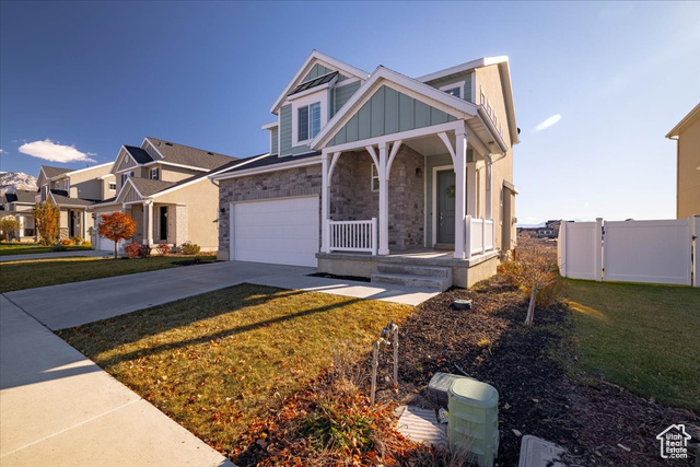 View of front facade featuring a garage, covered porch, and a front lawn