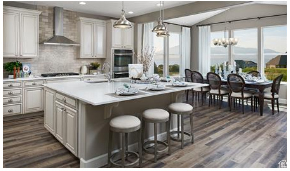 Kitchen featuring oven, a healthy amount of sunlight, wall chimney range hood, and an island with sink. Photos are of a Helena but not the subject property.