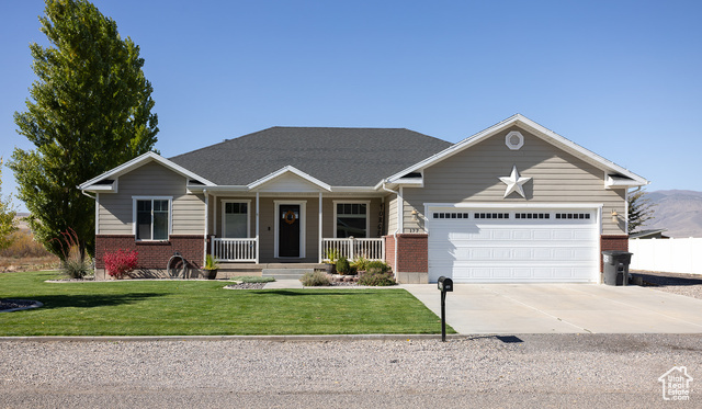 View of front facade featuring a front yard, a garage, and a porch